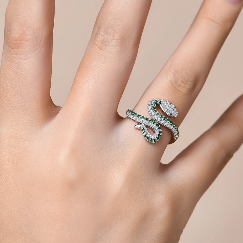Silver ring with green gemstones on a black surface, followed by a close-up of the ring on a hand.