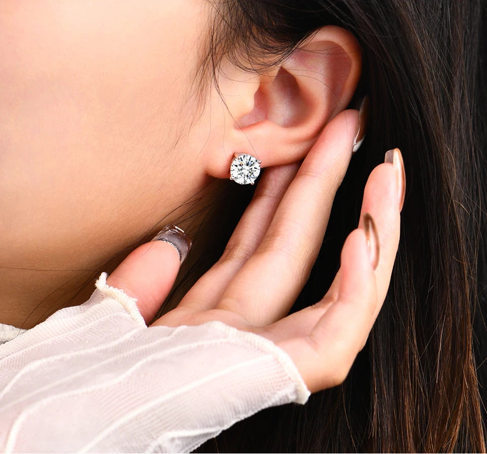 Close-up of a person wearing a diamond earring with a hand adjusting it.