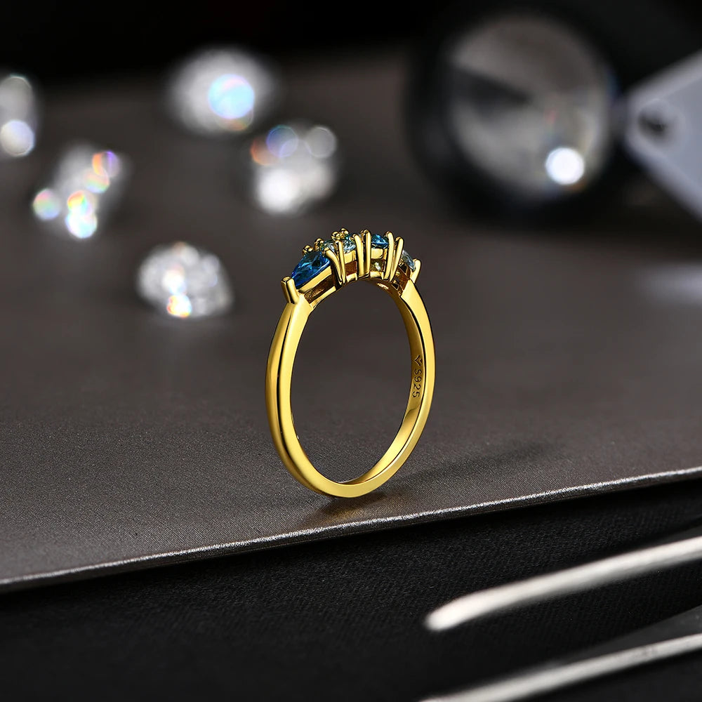 Gold ring with blue gemstones on a dark surface