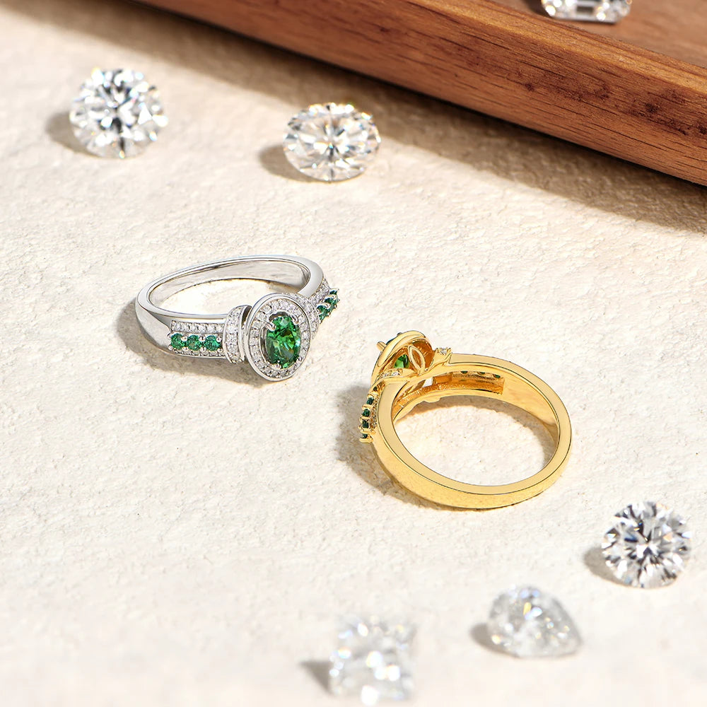 Gold and silver rings with green gemstones on a beige surface