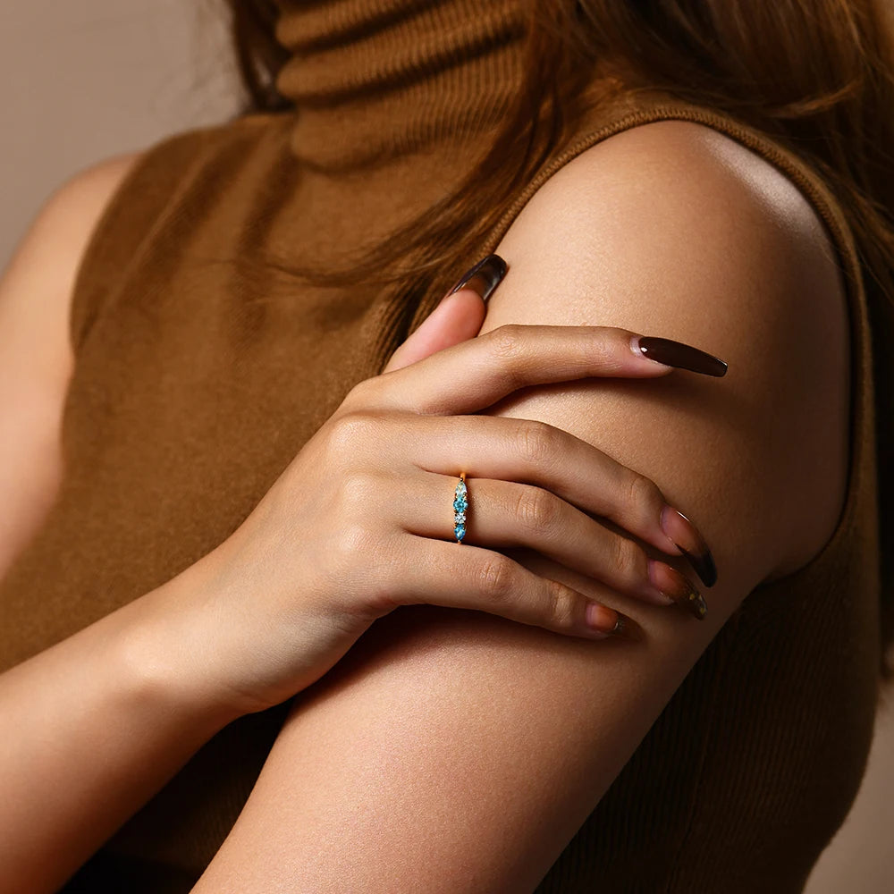 Woman wearing a blue ring on her finger with a neutral background